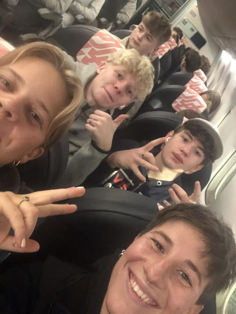 5 boys on their way to Canada sit in an aeroplane and smile