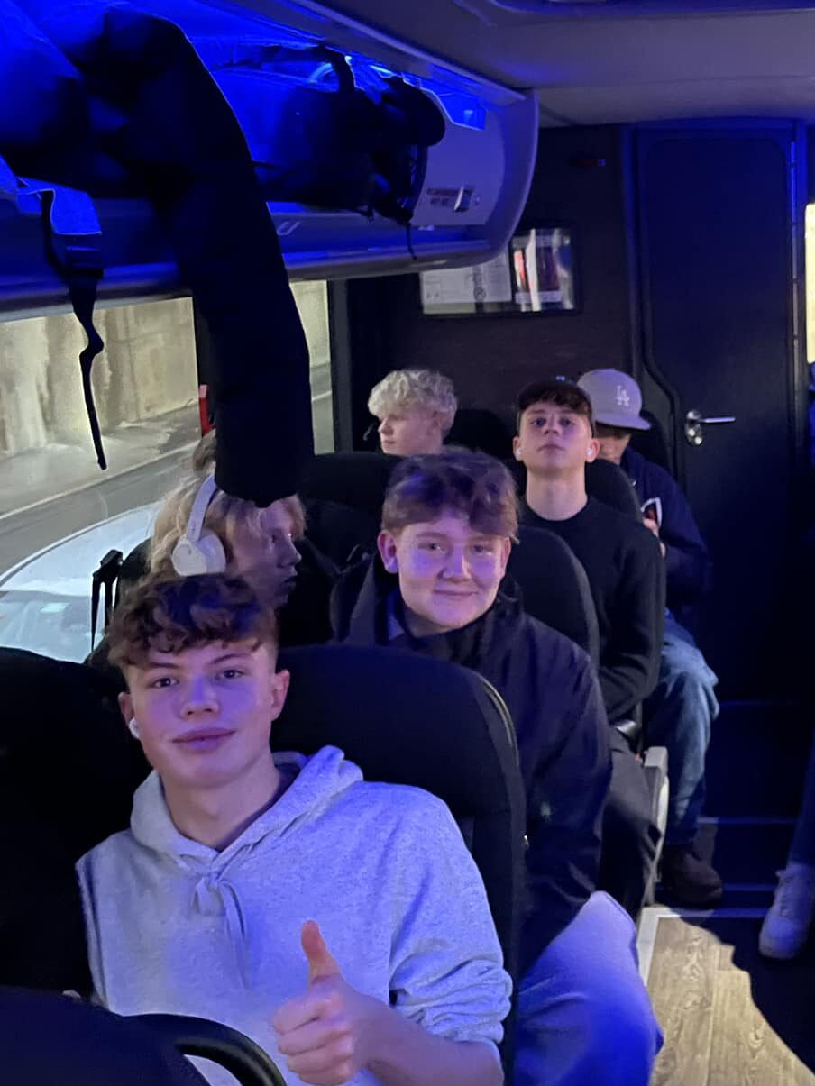 6 drenge sidder i bus og smiler