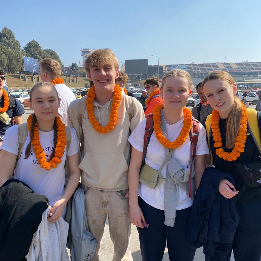 A boy and three girls together, each wearing an orange necklace