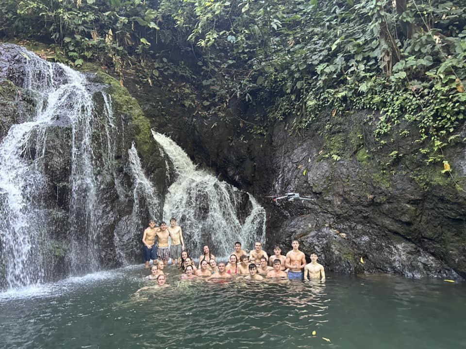 Students gathered in front of a waterfall in Costa Rica