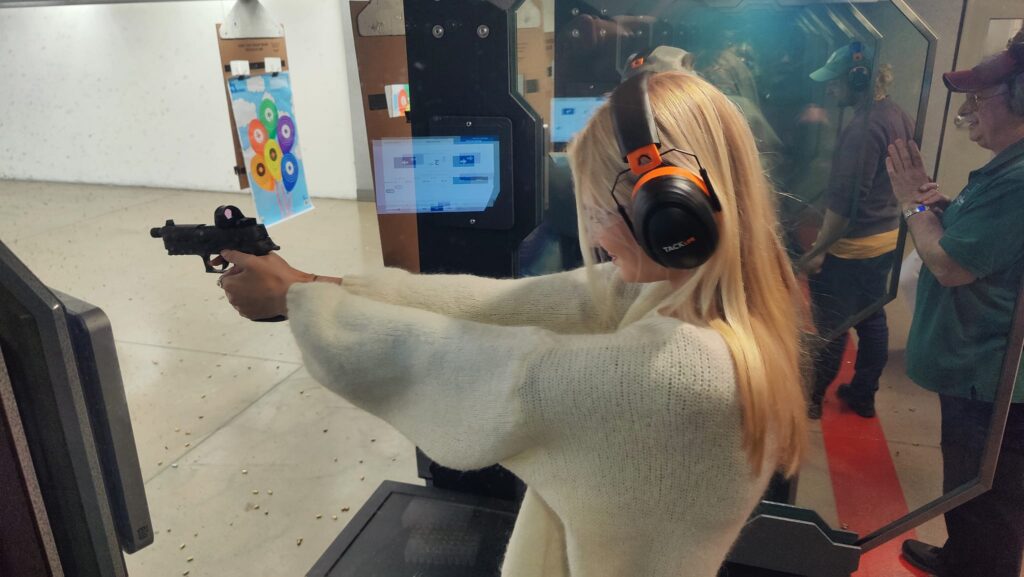 Pige står med en pistol i hånden og skyder 