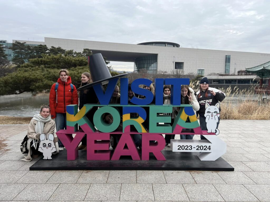 Elever står bag kæmpe skilt hvor der står Visit Korea Year