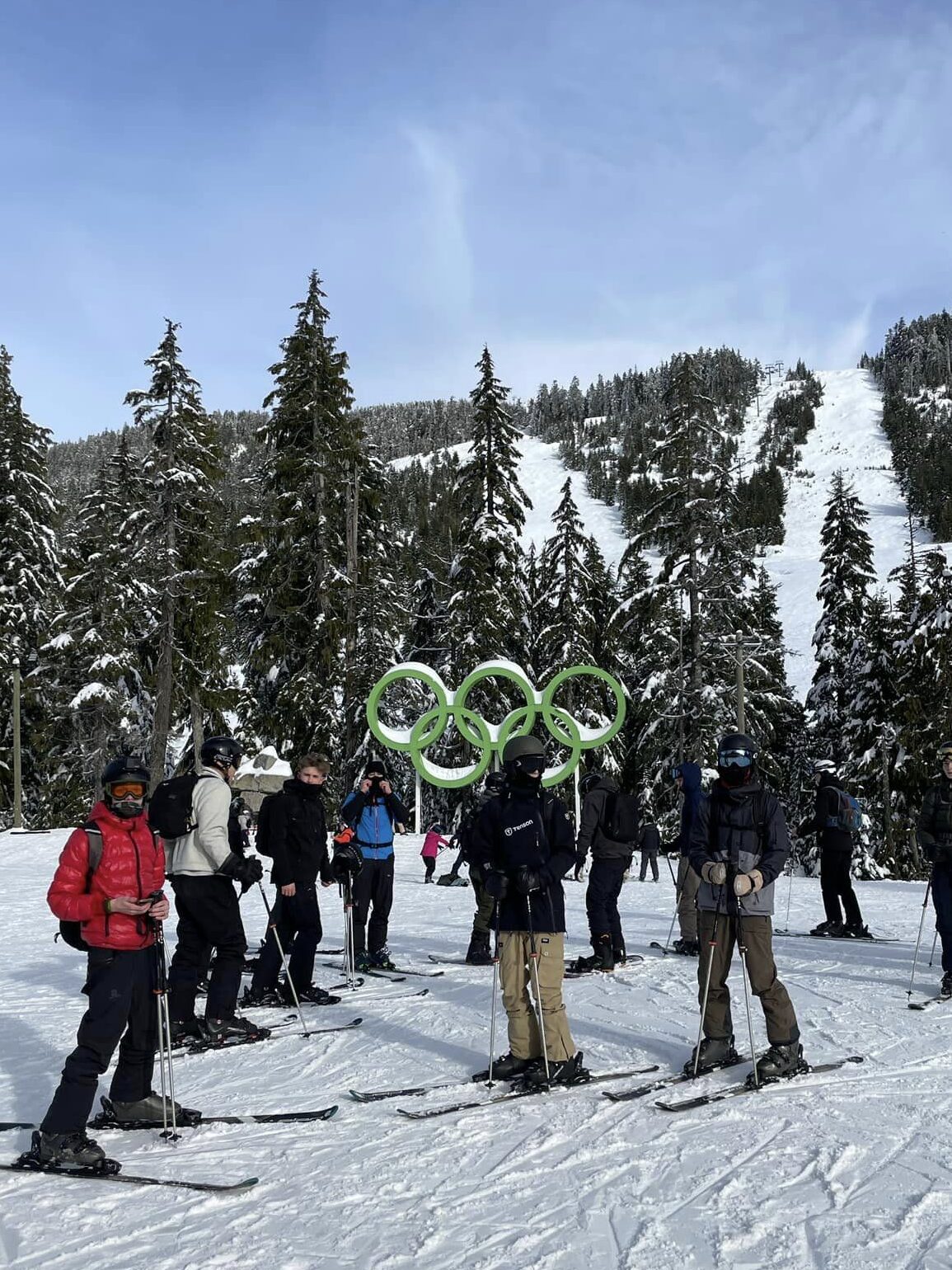 Efterskoleelever står på ski med 5 olympiske ringe bag dem