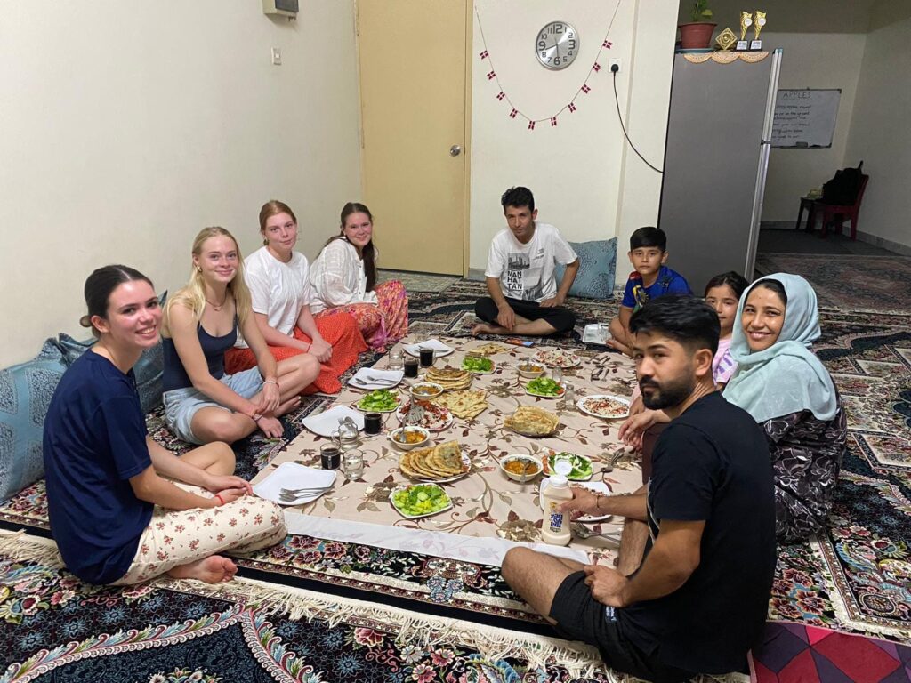 After-school students sit on the floor and have dinner with a Malaysian family