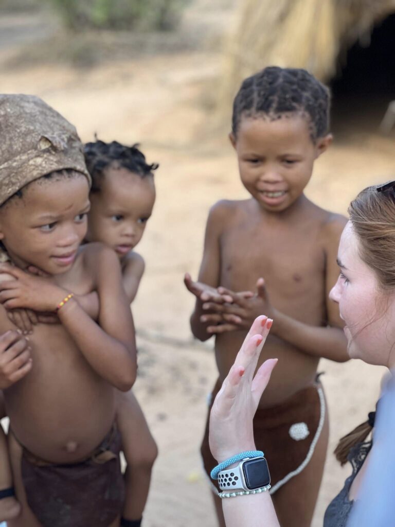 dansk efterskoleelev giver high fives til yngre børn fra Namibia