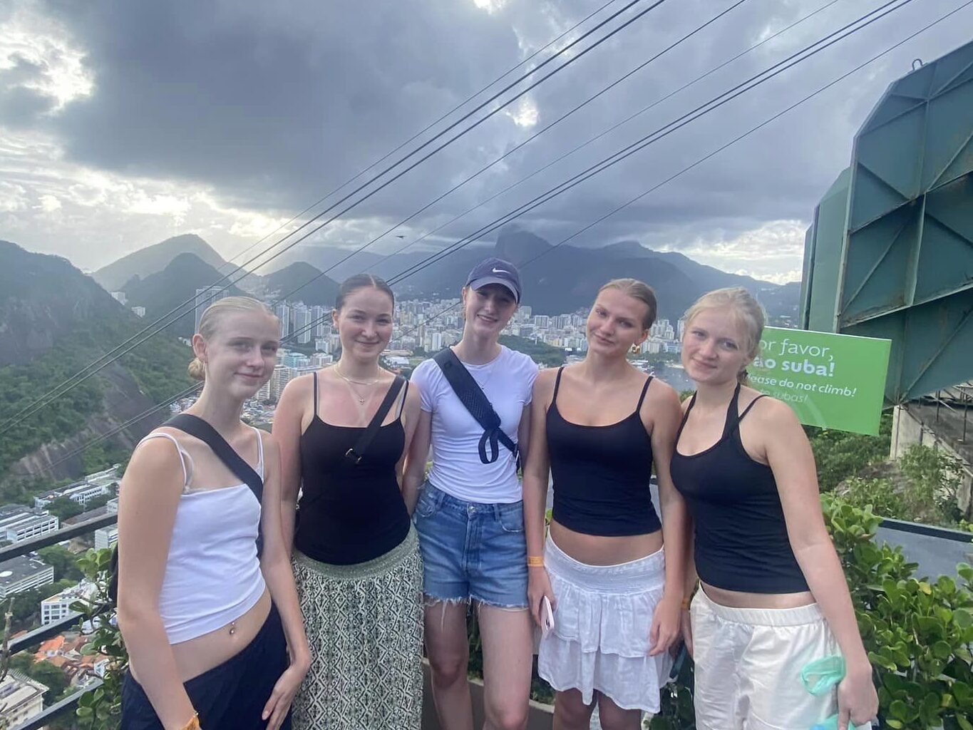 Girls stand together with mountains and city in the background.