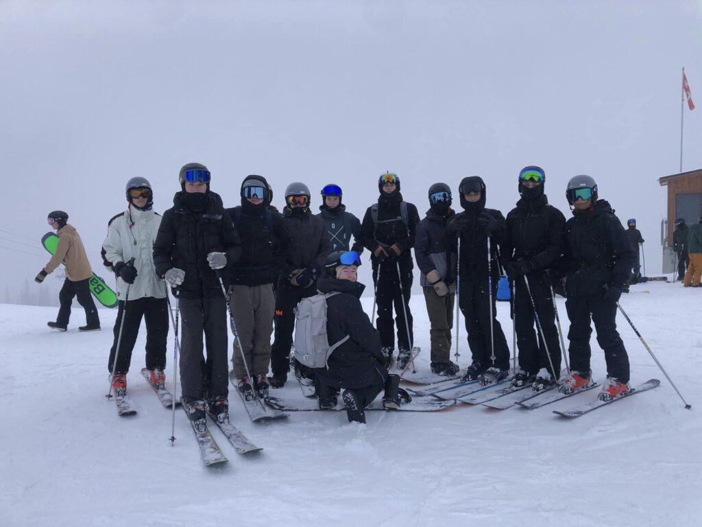 Elever står samlet på ski og er omgivet af sne