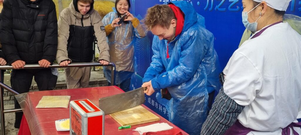 A boy chops a piece of meat with a giant knife