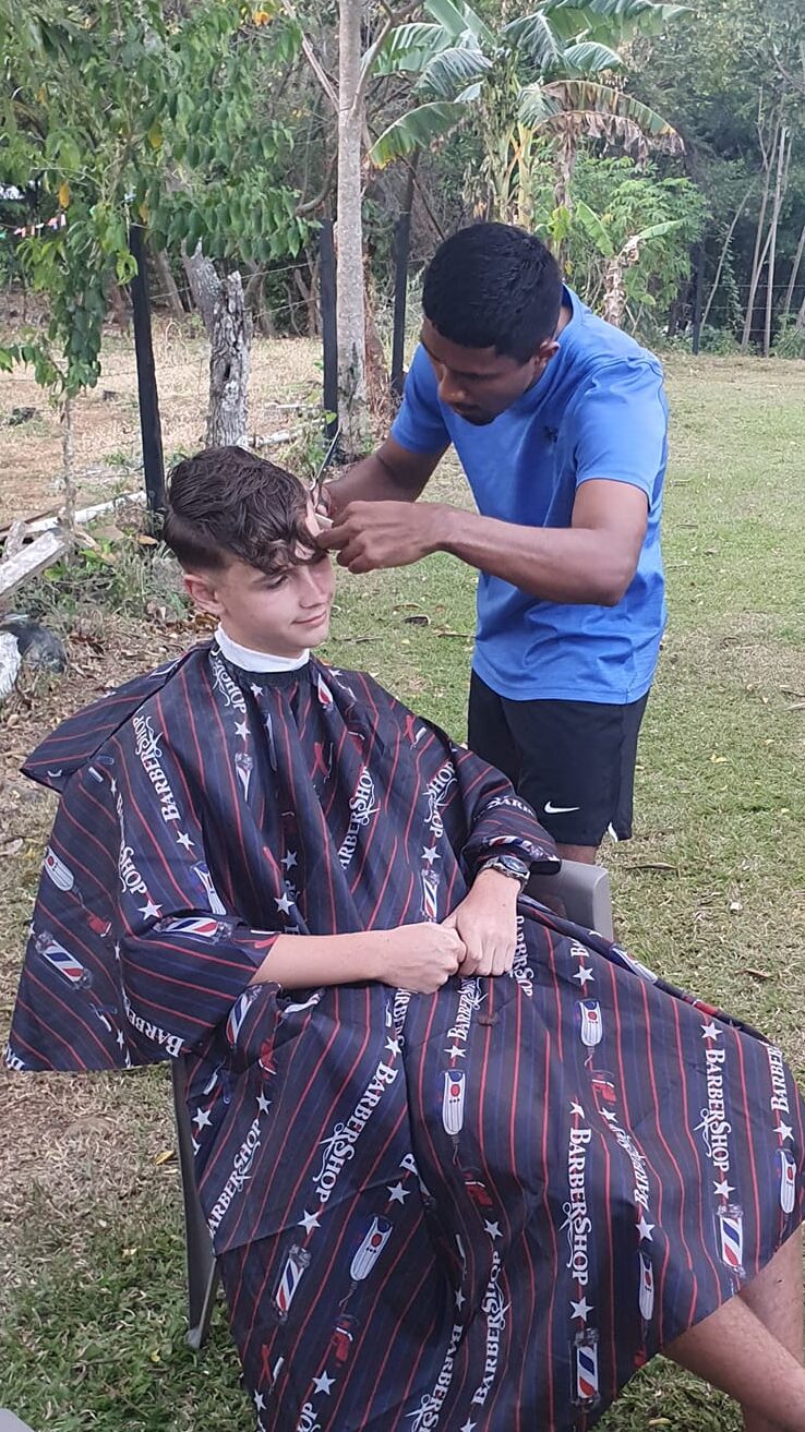 A boy gets a haircut by a man from Panama