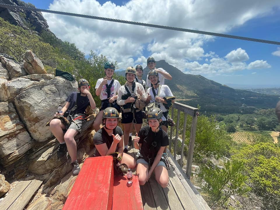 girls and boys together with blue sky and mountains in the background