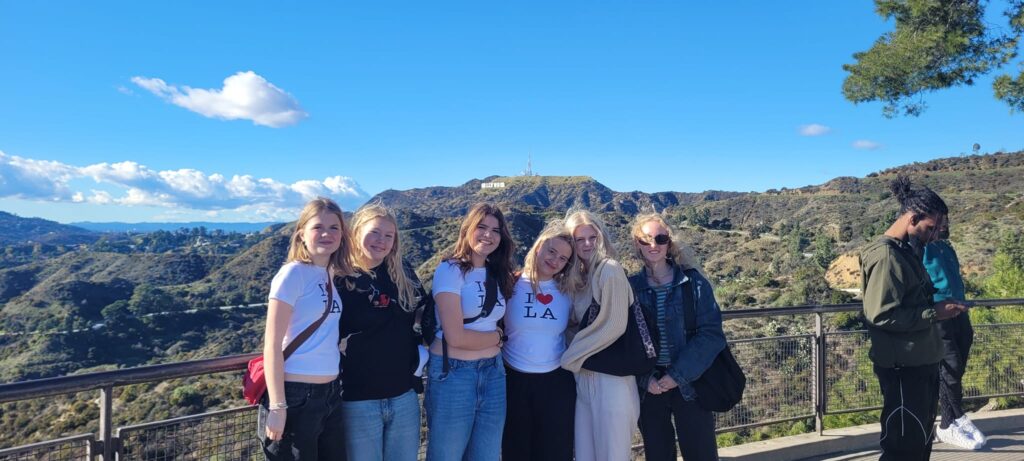 five girls stand in front of the Hollywood sign in the USA