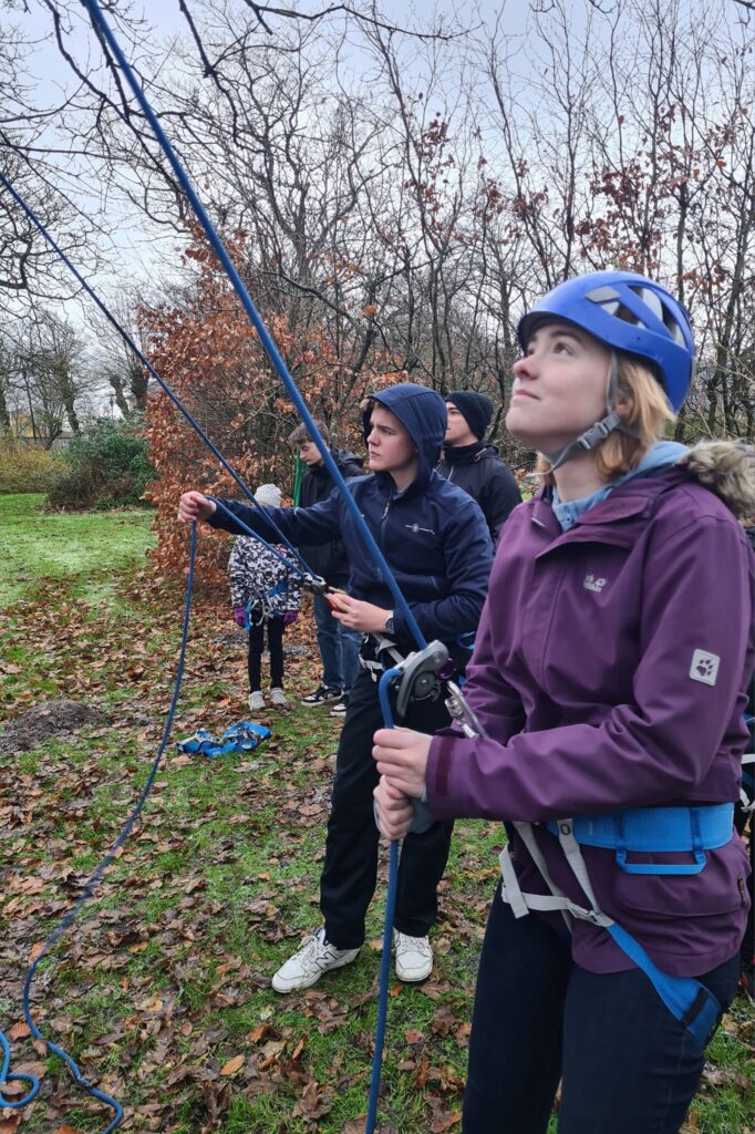 A girl and a boy pull a rope while standing outside