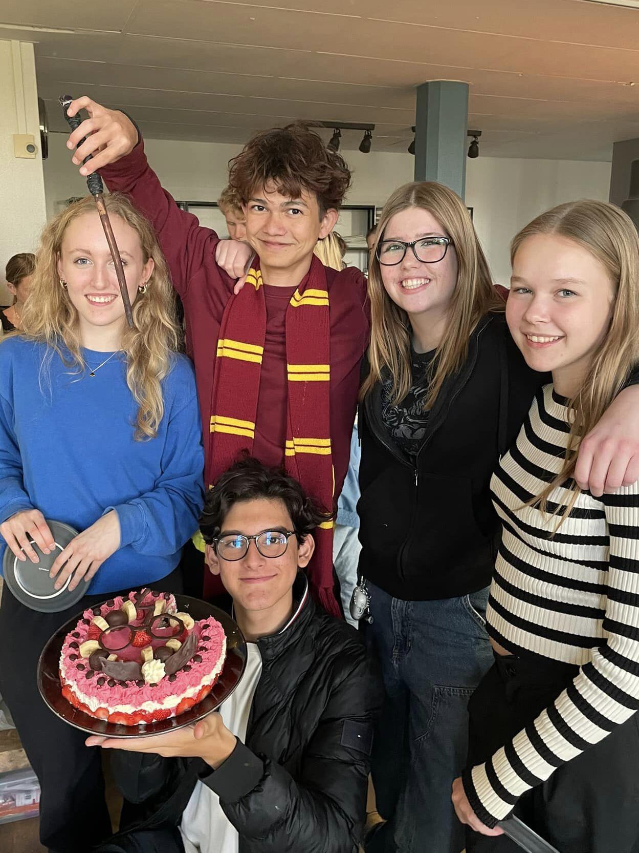 Group stands together and shows off a cake