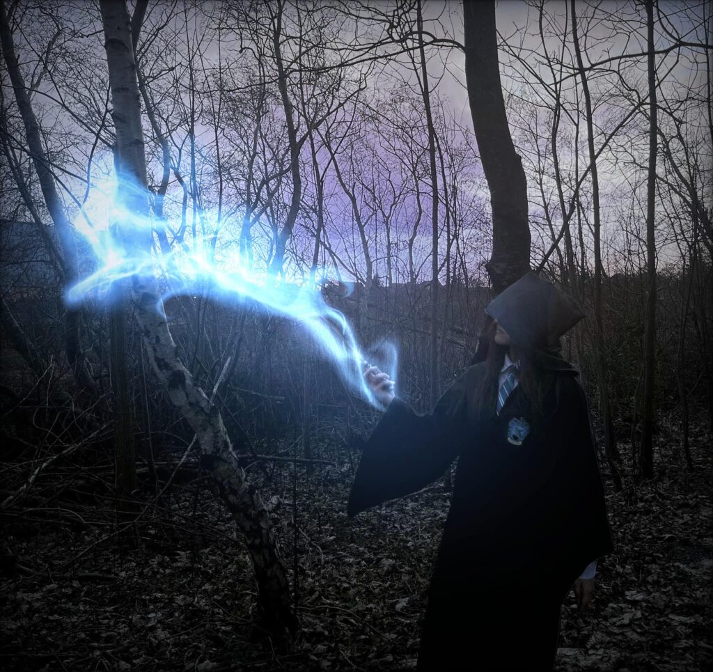 a boy stands in a forest and performs magic with his wand