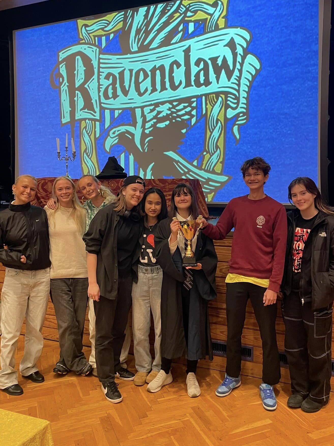 A group of students large together in front of a Ravenclaw sign