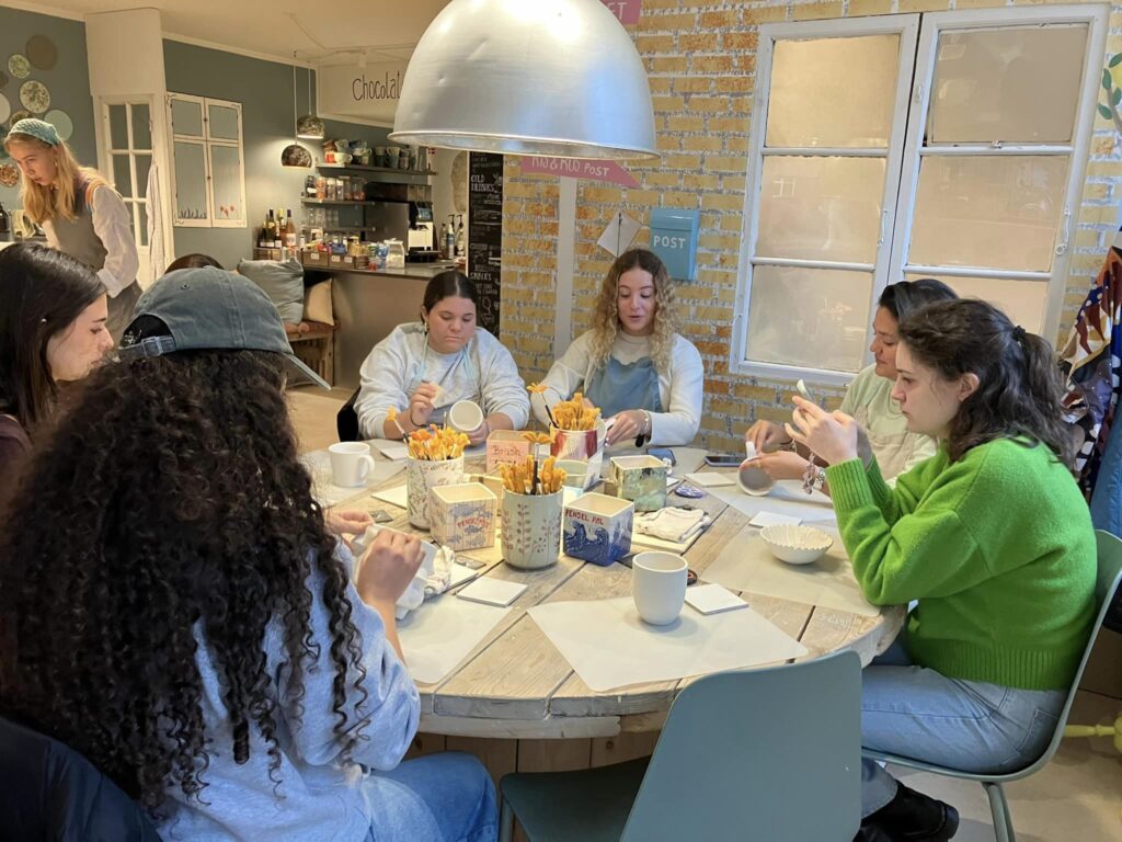 two girls sit at a drill and paint pottery