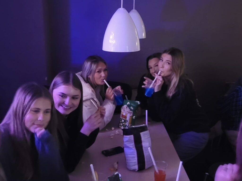 En gruppe af piger sidder ved et bor og drikker drinks