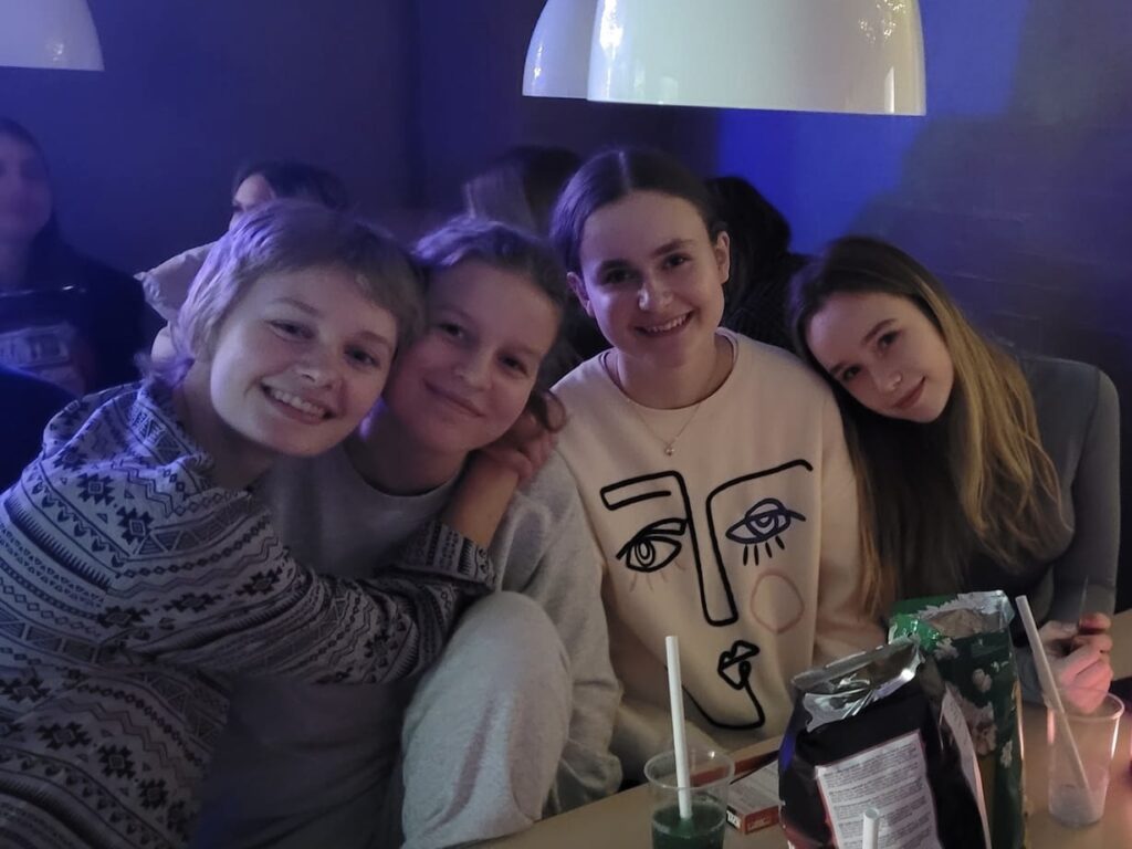 four girls sit together and smile as they hold each other