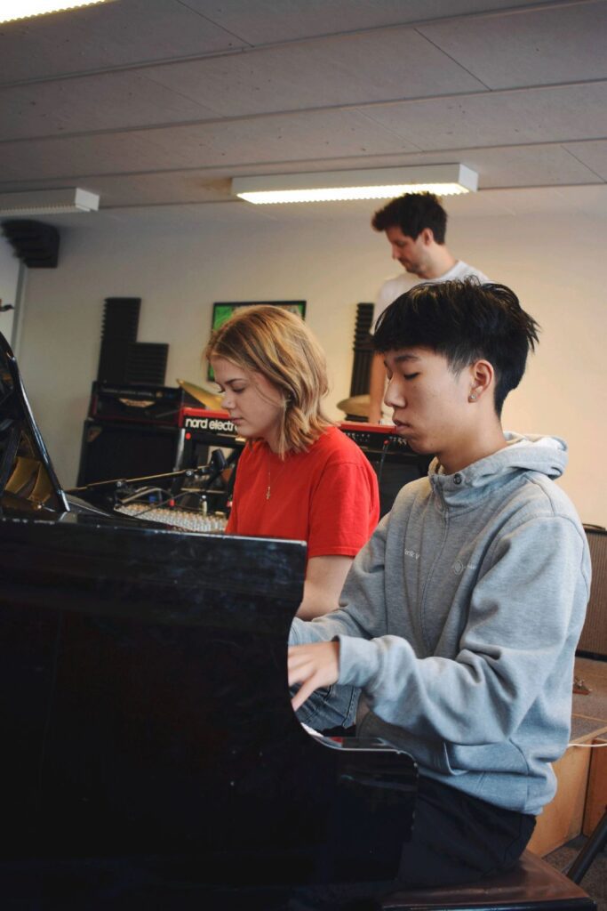 A girl and a boy sitting at the piano