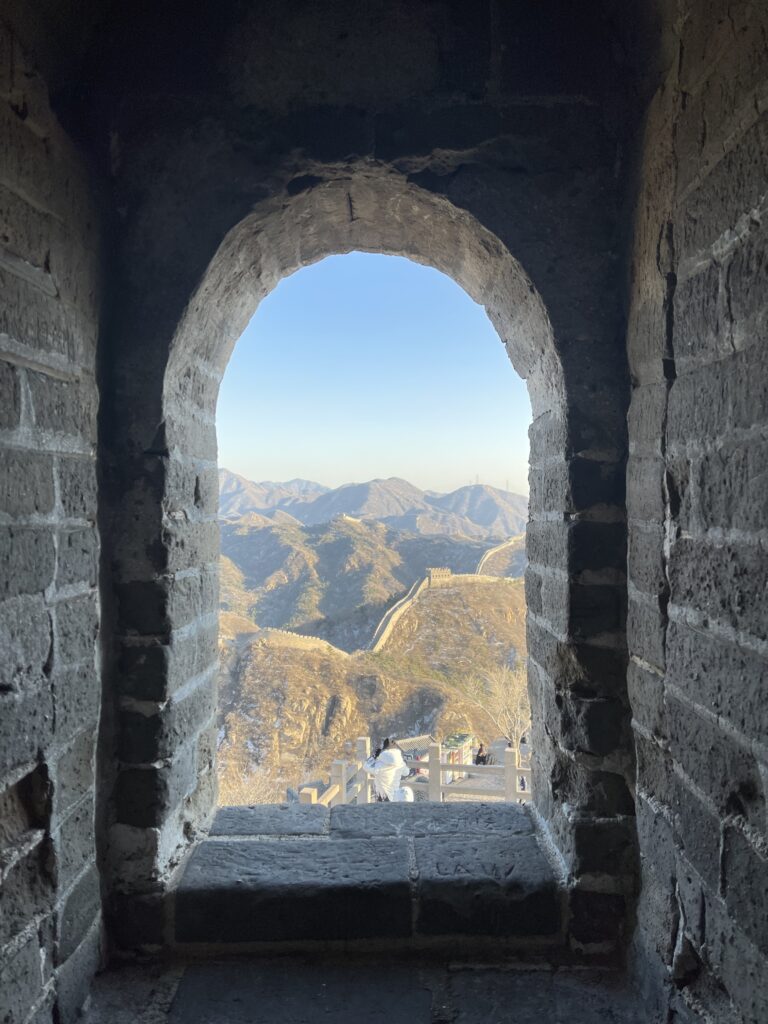 A hole through a thick wall shows mountains through it