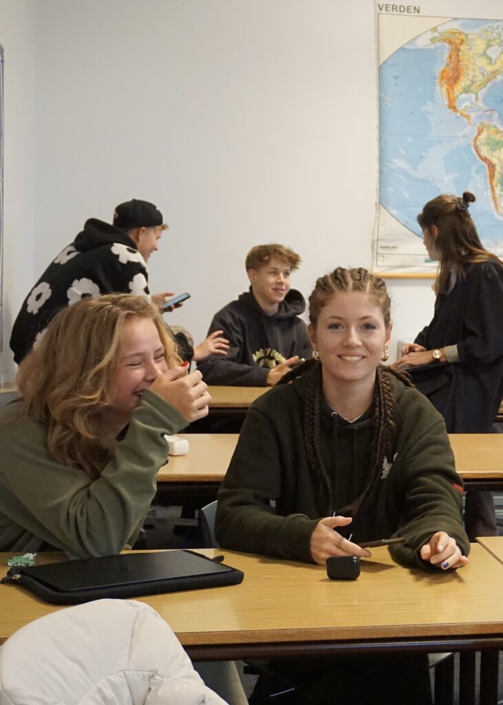 To piger fra Ranum Efterskole College sidder ved et bord og griner