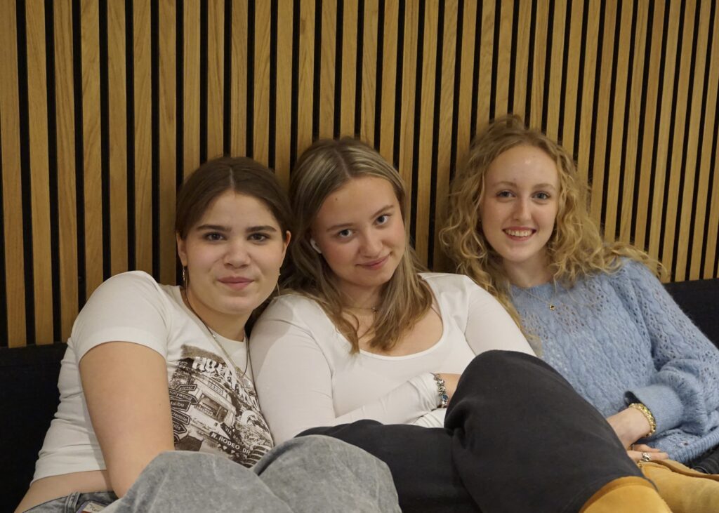 Three girls from Ranum Efterskole College sit close together and smile