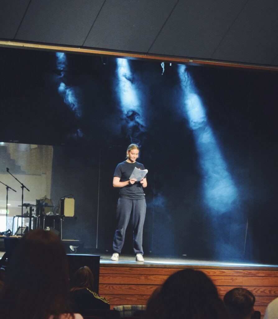 A girl stands on a stage with smoke