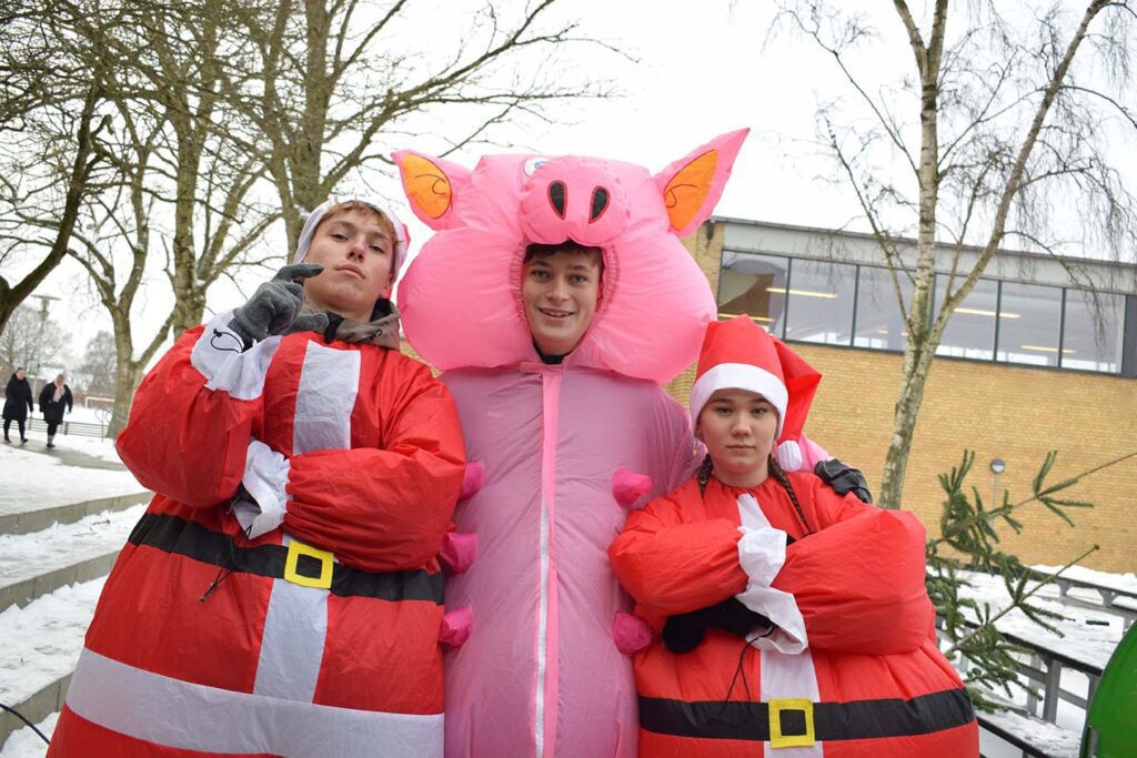 To drenge og en pige er udklædt som oppustelig gris og julemænd