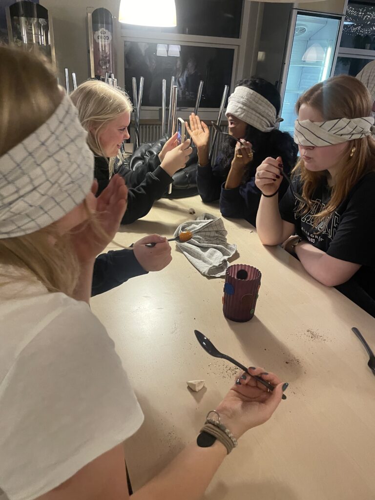 A larger group sits together blindfolded 