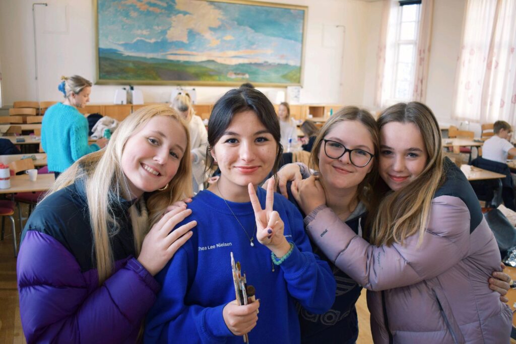 Four girls stand together and smile