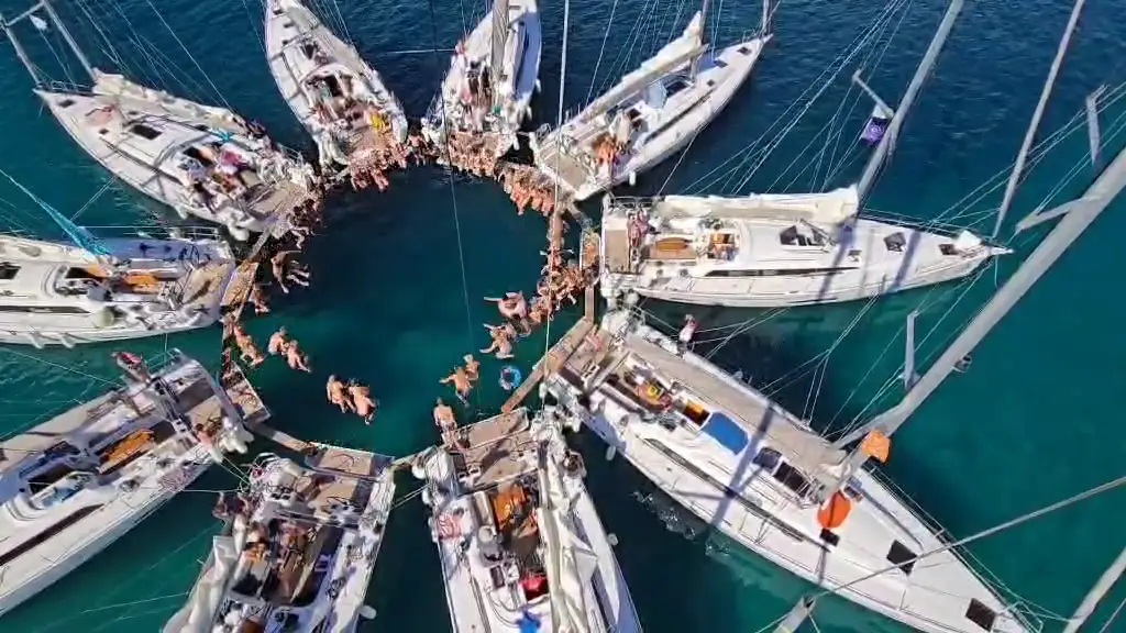 The sailing team ends the journey with a joint jump into the water, surrounded by all the boats.
